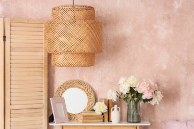 Yatak odasında ayna, kitaplar ve güzel şakayıklar olan bir komodin.