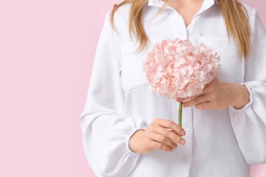 Woman with hydrangea flower on pink background, closeup