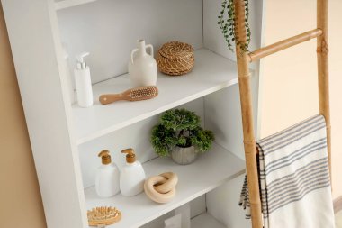 Banyo aksesuarlı raflar. Odada bej duvarın yanında.