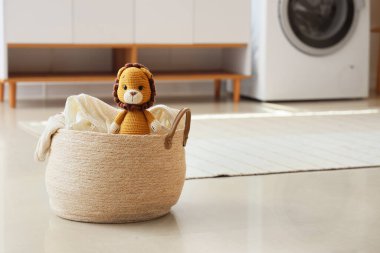 Çamaşır sepetinde yerde oyuncak aslan var.