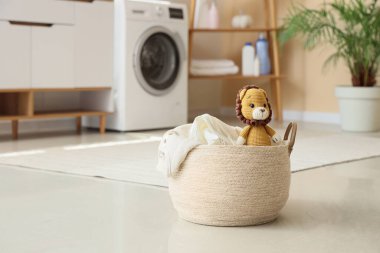 Çamaşır sepetinde yerde oyuncak aslan var.