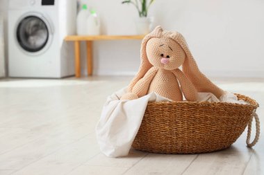 Wicker basket with toy bunny on floor in laundry room