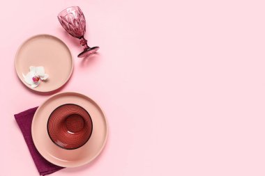 Pembe arka planda orkide çiçeğiyle güzel bir masa.