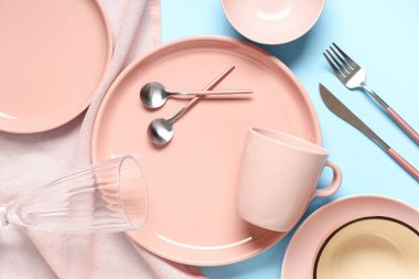 Mavi arka planda gümüş çatal bıçak seti olan güzel bir masa.