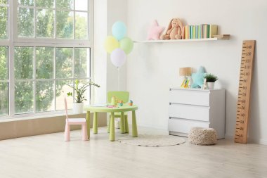 Kitaplığı, masası ve oyuncakları olan hafif çocuk odasının içi.