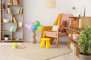 Interior of light children's room with bookshelves, armchair and toys