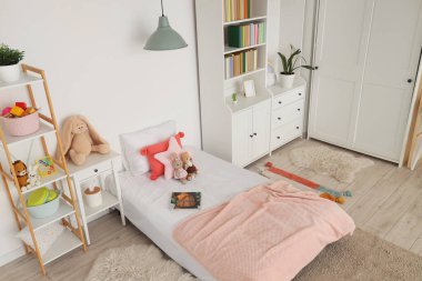 Interior of light children's room with bookshelf, bed and toys
