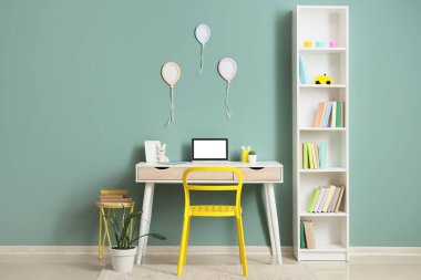 Kitap rafı ve çalışma masası olan çocuk odasının içi