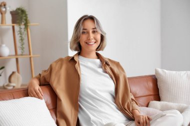 Beautiful woman sitting on brown sofa at home