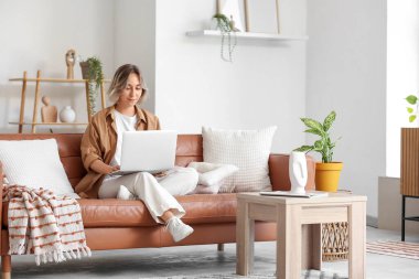 güzel bir kadın evde kanepede dizüstü kullanarak
