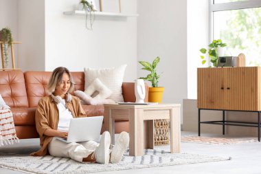 Evde dizüstü bilgisayar kullanan güzel bir kadın.