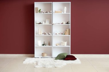 Pamuk çiçekli raflar, kitaplar ve dekorasyon odasının yanındaki bordo duvarda.