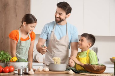Happy father with his children cooking pasta in kitchen