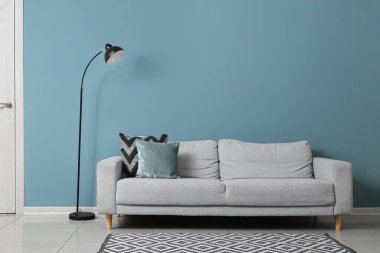 Oturma odasındaki yeşil duvarın yanındaki siyah lamba ve kanepe.