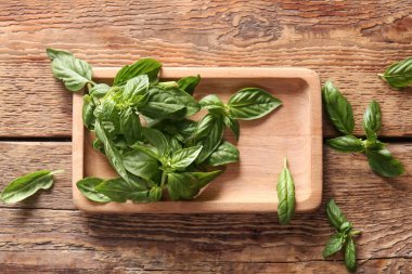 Ahşap arka planda taze fesleğen yapraklı tepsi