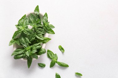 Beyaz arka planda taze yeşil fesleğen yapraklı kase