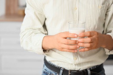 Mutfakta bir bardak sütle genç bir adam, yakın plan.