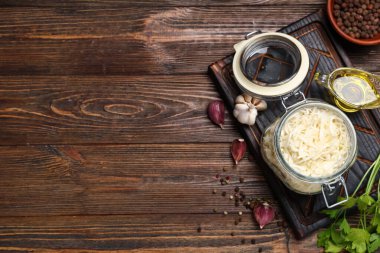 Lezzetli lahana turşulu kavanoz ve ahşap arka planda farklı baharatlar.