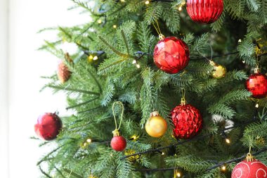 Kırmızı topları olan Noel ağacı ve beyaz arka planda parlayan ışıklar, yakın plan