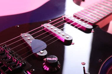 Pembe arka planda modern elektro gitar, yakın plan.