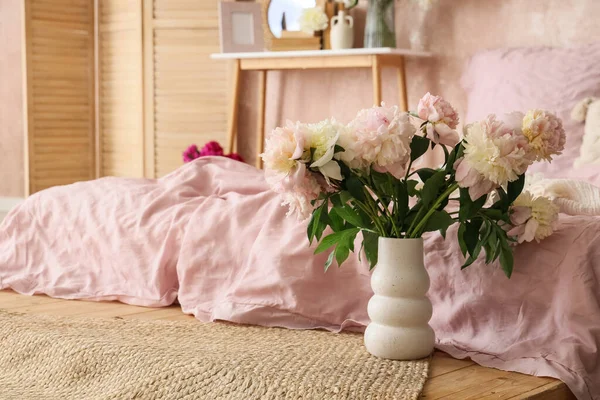 Yatak odasındaki rahat yatağın yanında bir buket güzel şakayık.