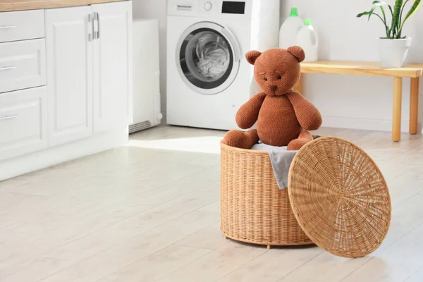 Wicker basket with toy bear in laundry room