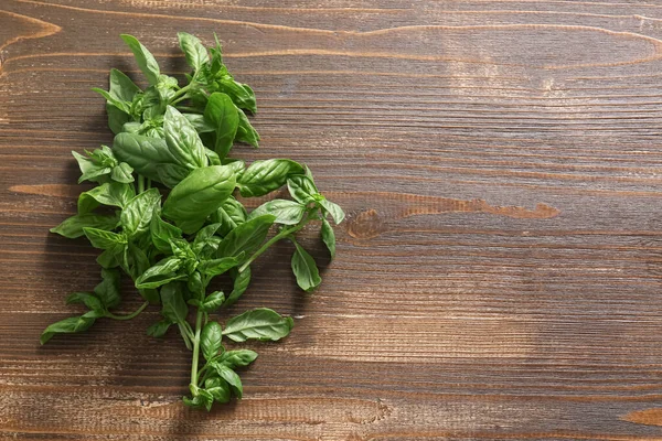 Tahta arka planda taze yeşil fesleğen yaprakları