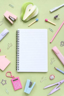 Yeşil arka planda farklı kırtasiye malzemesi içeren defter