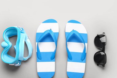 Güneş gözlüklü ve gri arka planda şnorkelli kadın tarzı terlikler.