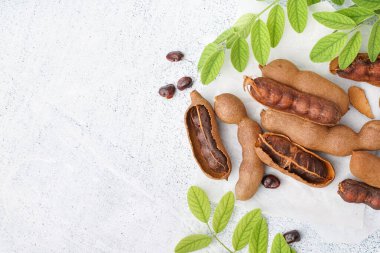 Beyaz arka planda lezzetli tamarindler, yapraklar ve tohumlar