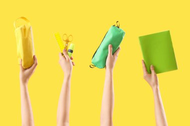 Sarı arka planda farklı kırtasiye malzemesi olan kadın elleri