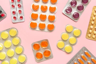 Pembe arka planda su toplayan paketlerdeki farklı haplar.