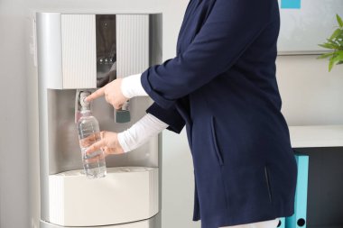 Plastik şişeyi soğutucudan filtreli suyla dolduran kadın.