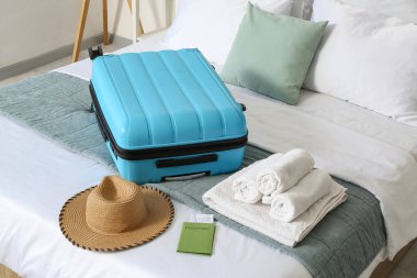 Bavul, havlu, şapka ve pasaport otel odasındaki yatağın üstünde.