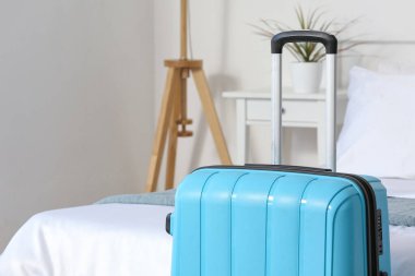 Hafif otel odasında, yatağın yanında bavul, yakın plan.