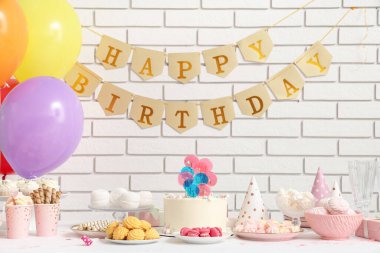 Beyaz tuğla duvara karşı doğum günü partisi için pasta, şeker ve dekor.