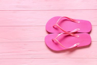 Plaj terlikleri pembe ahşap arka planda