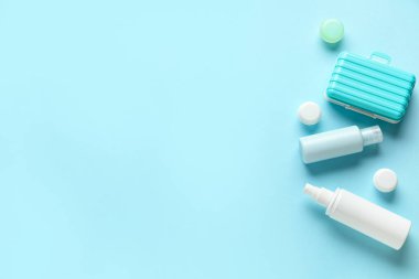 Renkli arka planda seyahat kozmetik seti ve mini bavul kompozisyonu