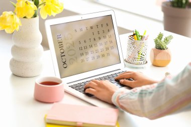 Masada takvimi olan dizüstü bilgisayar kullanan kadın eller, yakın plan