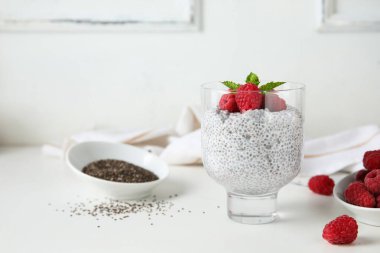 Bir bardak taze ahududu ve beyaz arkaplanda nane aromalı Chia tohumu pudingi.