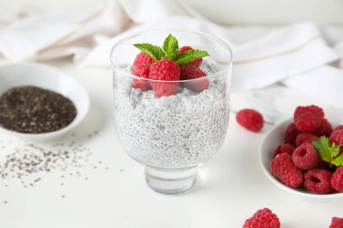 Bir bardak taze ahududu ve beyaz arkaplanda nane aromalı Chia tohumu pudingi.