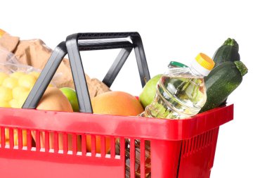 Beyaz zemin üzerinde farklı taze ürünler bulunan kırmızı alışveriş sepeti, yakın plan