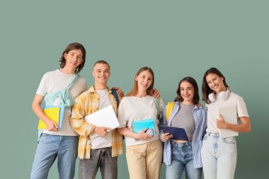 Group of students with laptops and notebooks on green background