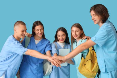 Group of medical students putting hands together on blue background