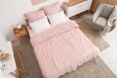 Bed with stylish pink bedding, folding screen, commode, armchair and table in bedroom, top view