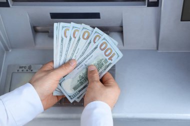 Male hands withdrawing dollar banknotes from ATM, closeup