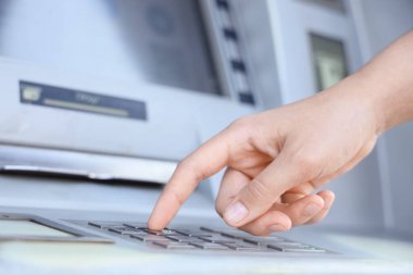 Female hand entering card's PIN code at ATM, closeup