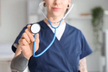 Tattooed female doctor with stethoscope in clinic, closeup