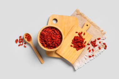 Ahşap kase ve kaşık, gri arka planda kırmızı, kurutulmuş goji üzümleri.