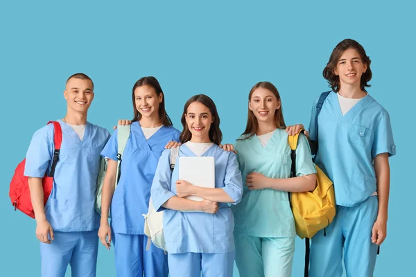 Group of medical students with backpacks and laptop on blue background